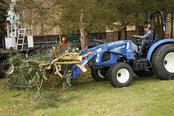 image of worker picking up tree branches with a tractor